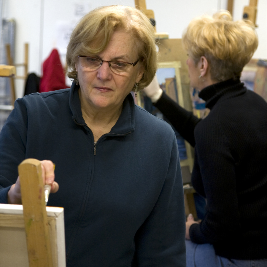 Two women painting on easels in an art class